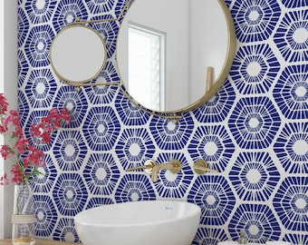 May include: A white ceramic vessel sink sits on a wooden counter in front of a wall with a blue and white geometric pattern. Above the sink, a gold-toned wall-mounted faucet and a dual-mirror fixture with gold frames are mounted on the wall.