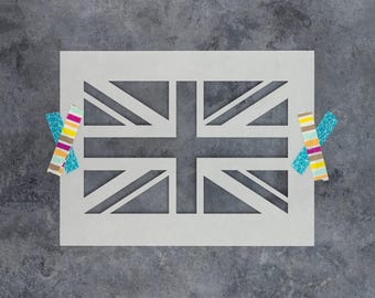 May include: A rectangular stencil featuring a cut-out design of the Union Jack flag. The stencil is off-white and is secured on both the left and right sides by pieces of colorful patterned adhesive tape with stripes and geometric shapes.