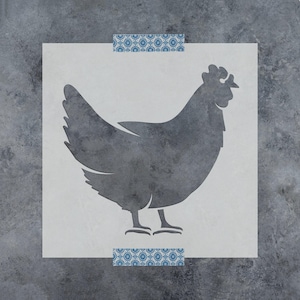 May include: A square stencil featuring a dark gray silhouette of a chicken in the center. The stencil is secured at the top and bottom edges with two strips of blue and white patterned decorative tape against a dark gray textured background.