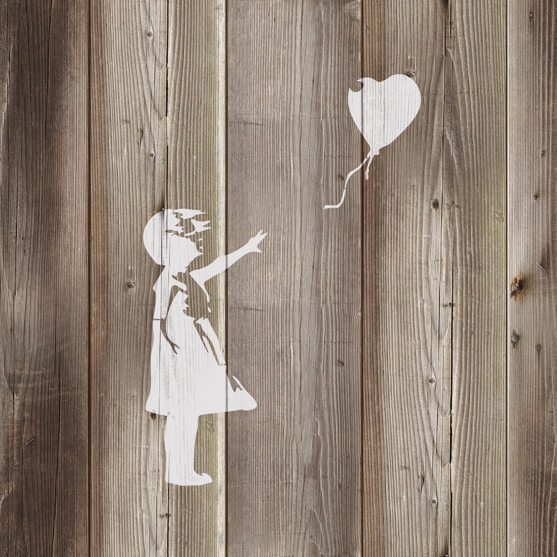 May include: A white stencil of a girl reaching out to a heart-shaped balloon on a wood panel background.