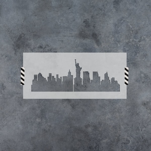 May include: A stencil of the New York City skyline with the Statue of Liberty in the center. The stencil is made of a thin, white material and is perfect for creating a unique and stylish design on walls, furniture, or other surfaces.