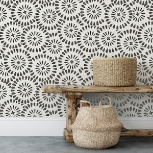 May include: A wallpaper featuring a repeating pattern of dark gray circular floral motifs on a white background. A woven basket sits on a wooden bench, while another woven basket is placed on the floor in front of the bench.