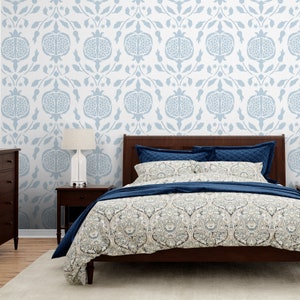 May include: A bedroom with a bed with a blue and white patterned duvet cover and a blue and white patterned headboard. The wall behind the bed is white with a blue and white patterned wallpaper featuring a pomegranate design.
