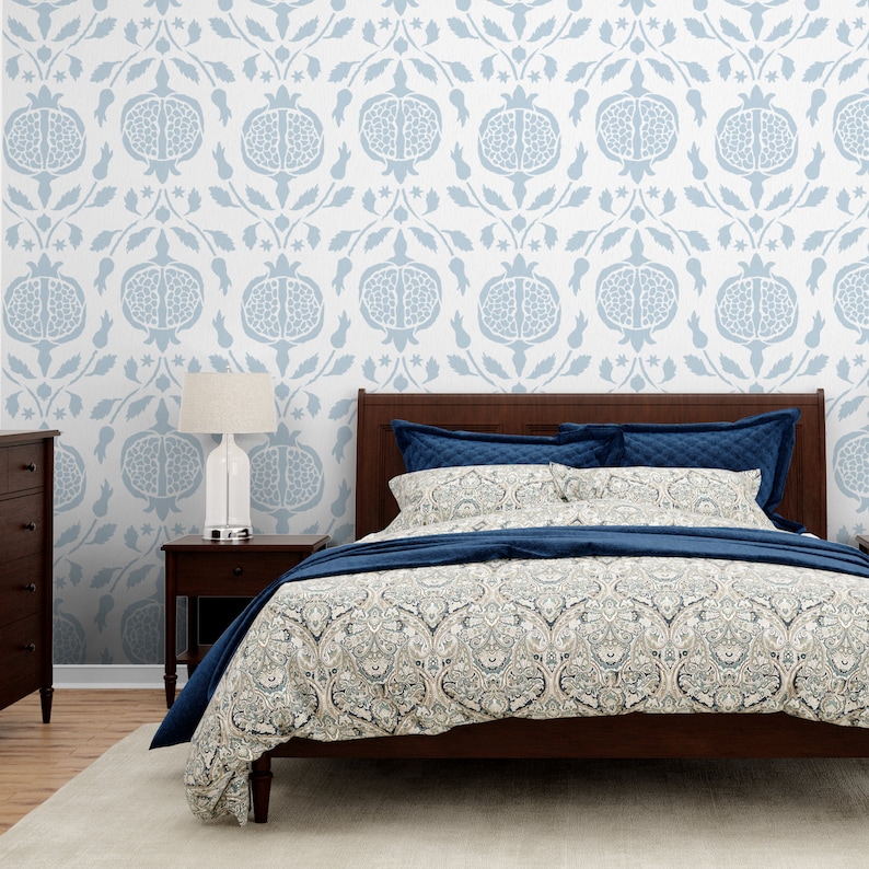 May include: A bedroom with a bed with a blue and white patterned duvet cover and a blue and white patterned headboard. The wall behind the bed is white with a blue and white patterned wallpaper featuring a pomegranate design.