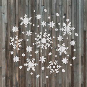 K&ouml;nnte beinhalten: Ein wei&szlig;er Holzgrund mit einem Muster aus wei&szlig;en Schneeflocken, die darauf gemalt sind. Die Schneeflocken sind in einem Kreis um die Mitte des Bildes angeordnet.
