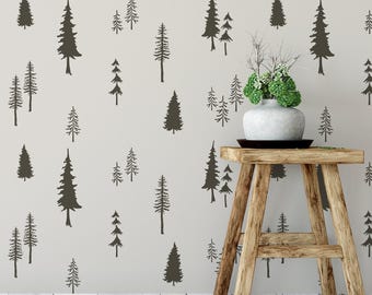 May include: A light gray wall featuring a repeating pattern of dark brown pine tree silhouettes. A light-colored ceramic vase containing green foliage sits on a four-legged wooden stool with a natural grain finish and a dark circular base.