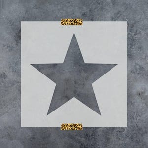 May include: A square stencil featuring a large, centered five-pointed star cutout. The stencil is light gray and is secured at the top and bottom edges with two strips of adhesive tape that have a brown and black leopard print pattern.