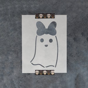 May include: White stencil of a ghost with a large bow on its head. The ghost has two eyes and a smiling mouth.