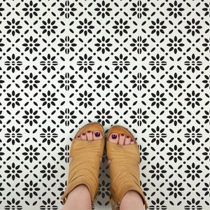 May include: A pair of brown ankle boots with black nail polish on the toes, standing on a white floor with a black and white geometric pattern.