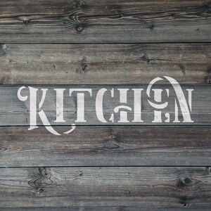 May include: A rustic wooden sign with the word "KITCHEN" in large, white, decorative lettering. The sign is made of weathered, gray-toned wooden planks, creating a vintage aesthetic. The text is centered and stands out against the wood.