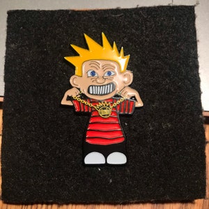 May include: A yellow-haired cartoon character with a red and black striped shirt and a gold chain with a pendant. The character is wearing a gold chain with a pendant. The character has a mischievous expression on its face.