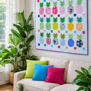 Könnte beinhalten: Eine weiße Steppdecke mit bunten Ananas-Designs hängt über einem cremefarbenen Sofa mit grünen, blauen und rosa Kissen. Eine Ananas und Limetten liegen auf einem gewebten Couchtisch. Topfpflanzen sind im Hintergrund zu sehen.