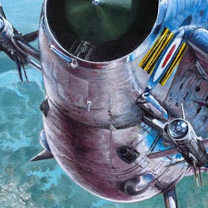 May include: A close-up of a silver and blue fighter jet with a red, white, and blue roundel on the side. The jet is flying over a green and blue landscape.