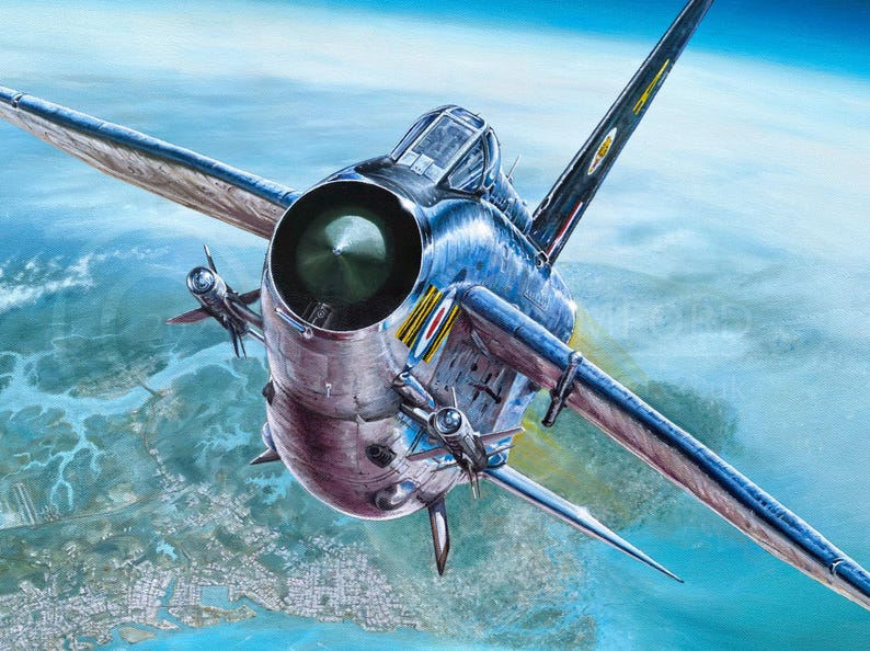 May include: A silver and blue fighter jet flies over a city and water. The jet has a large engine and a long, pointed nose.