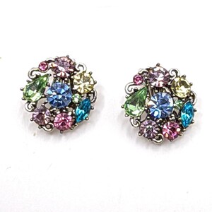 May include: A pair of silver tone earrings with a cluster of colorful rhinestones. The earrings feature a variety of colors including pink, blue, green, and light blue.