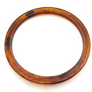 May include: A brown tortoiseshell plastic bangle bracelet.