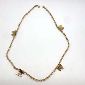 Può includere: Una collana color oro con un delicato design a catena. La collana è adornata con quattro piccoli ciondoli a farfalla, distribuiti uniformemente lungo la catena. Le farfalle hanno un aspetto strutturato, aggiungendo interesse visivo al gioiello.