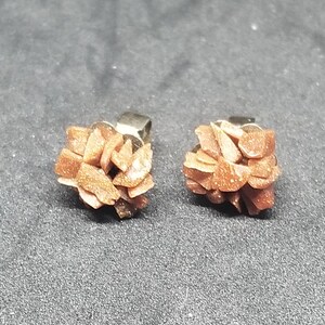 May include: A pair of gold-toned stud earrings with a cluster of small, brown, sparkly crystals.