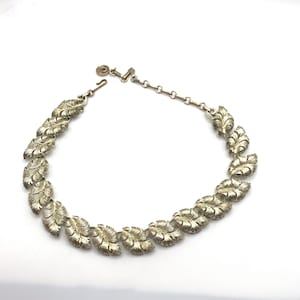 Puede incluir: Un collar de plata con una cadena y una serie de eslabones en forma de hoja.