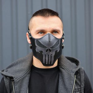 Peut inclure: Un masque facial en cuir noir avec un motif de cr&acirc;ne. Le masque a des sangles qui passent autour des oreilles et une boucle &agrave; l'arri&egrave;re.