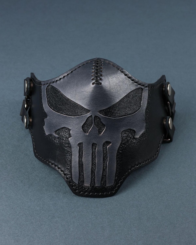 Peut inclure: Masque facial en cuir noir avec un motif de cr&acirc;ne cousu. Le masque est dot&eacute; de sangles r&eacute;glables avec des boucles m&eacute;talliques.