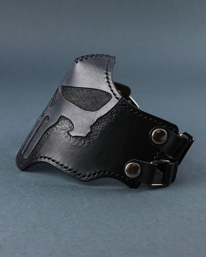 Peut inclure: Masque de moto en cuir noir avec un motif de cr&acirc;ne. Le masque a deux sangles r&eacute;glables avec des boucles m&eacute;talliques.