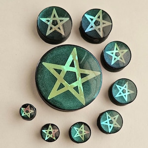May include: Set of eight green and gold iridescent pentagram ear gauges. The gauges are various sizes and are made of resin.