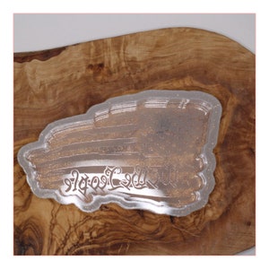 May include: Clear plastic mold with a gold glitter design of a stylized eagle with the text "God Bless America" underneath.