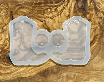 May include: Clear silicone mold for making resin earrings in the shape of cowboy boots. The mold has two boot shapes and two small circles for earring posts.
