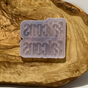 May include: A clear silicone mold with the word "scones" written twice in a glittery, white font.