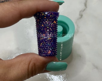 May include: A purple and iridescent glitter resin mold with a textured surface. The mold is being held by a hand.