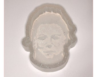 Könnte beinhalten: Ein weißer Glitzer-Schlüsselanhänger aus Harz mit der Silhouette der Maske von Michael Myers aus der Halloween-Reihe.