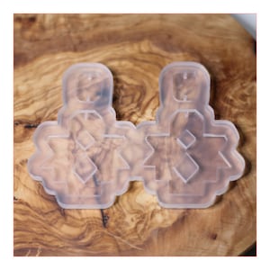 Puede incluir: Molde de silicona transparente para hacer pendientes. El molde presenta dos diseños de pendientes, cada uno con una forma geométrica y un agujero para un gancho.