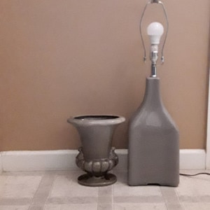 May include: A gray ceramic lamp with a white light bulb and a gray ceramic urn.