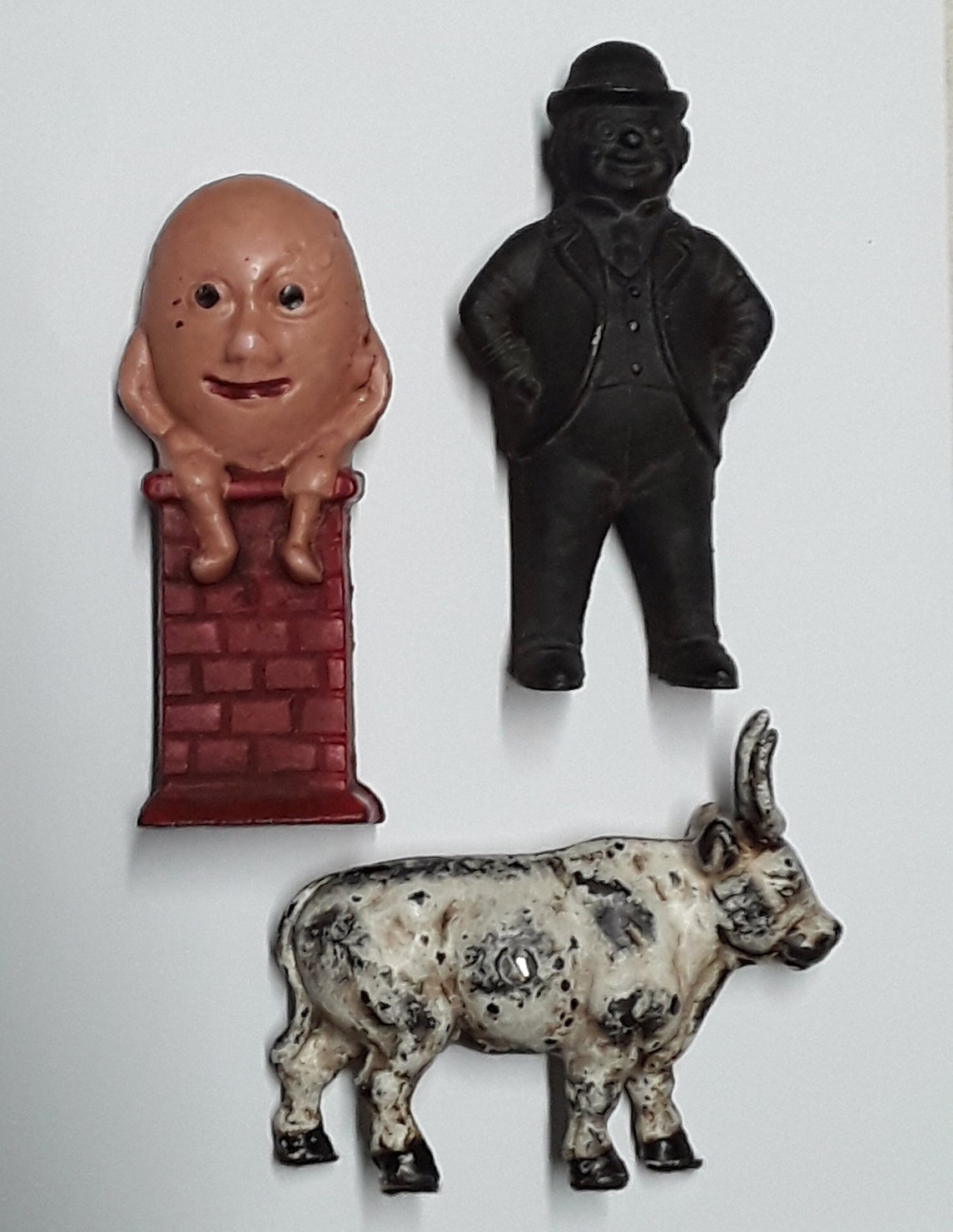 Three Vintage Cast Iron Still Banks, Including Cow, Humpty Dumpty, and