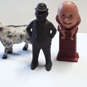 Three Vintage Cast Iron Still Banks, Including Cow, Humpty Dumpty, and Early 20th Century A C Williams Businessman