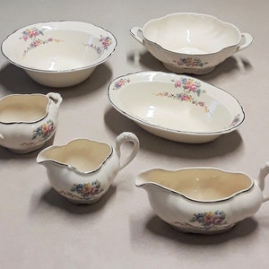 Könnte beinhalten: Satz von sechs Vintage-Porzellanschalen mit Blumendesigns. Die Schalen sind weiß mit schwarzem Rand und haben ein zartes Blumenmuster in Rosa-, Gelb- und Blautönen.