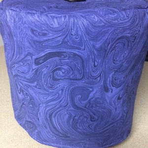 May include: A blue and black marbled fabric cover for a kitchen appliance. The cover has a black button on top.