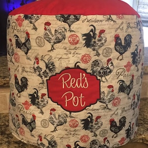 May include: Red and white kitchen appliance cover with a rooster pattern and the text "Red's Pot" embroidered in white on a red background.