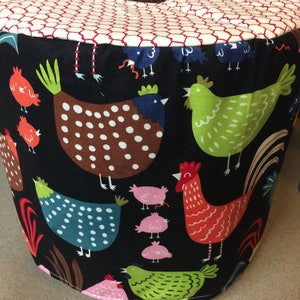 May include: A black fabric storage container with a red and white checkered top. The container features a colorful pattern of chickens and chicks.