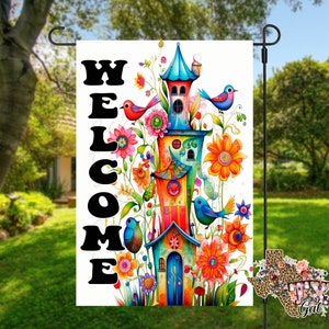 May include: A colorful welcome garden flag with a whimsical house design. The house is decorated with flowers, birds, and a welcome sign. The flag is perfect for adding a touch of whimsy to your garden.