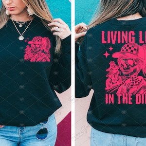 May include: Black sweatshirt with a pink graphic of a skeleton riding a dirt bike. The text "Living Life in the Dirt" is printed on the back of the sweatshirt.
