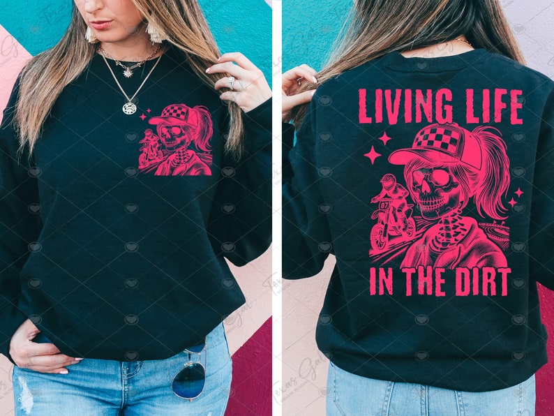 May include: Black sweatshirt with a pink graphic of a skeleton riding a dirt bike. The text "Living Life in the Dirt" is printed on the back of the sweatshirt.