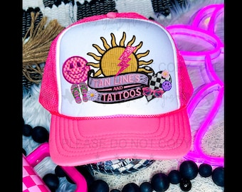 May include: Pink trucker hat with a white front panel featuring embroidered designs including a sun, lightning bolt, smiley face, flip flops, a daisy, a heart with a checkered pattern, sunglasses, and the text "Tan Lines and Tattoos".