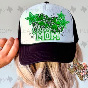 May include: Black and white trucker hat with a green and white pom-pom and stars. The hat has the text "Cheer Mom" on the front.