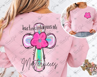 Puede incluir: Sudadera rosa con un diseño de cruz y el texto "Jesús convierte las piezas rotas en obras maestras".