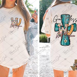 Puede incluir: Camiseta color crema con el texto "WV West Virginia" en un dise&ntilde;o floral y naranja en la parte delantera. La parte trasera de la camiseta muestra una cruz turquesa con las palabras "God Bless WV West Virginia".