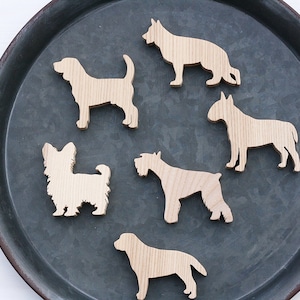 Könnte beinhalten: Sechs Holz-Silhouetten von Hunderassen auf einem dunkelgrauen Metalltablett. Die Silhouetten sind von einem Schäferhund, Beagle, Yorkshire Terrier, Schnauzer, Bullterrier und Labrador.