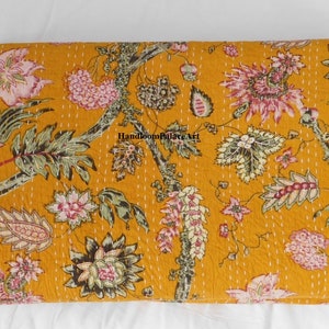 May include: A mustard yellow kantha quilt with a floral pattern in shades of pink, green, and brown. The quilt is hand-stitched and has a traditional Indian design.