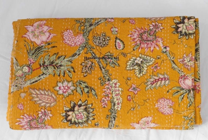 May include: A mustard yellow kantha quilt with a floral pattern in shades of pink, green, and brown. The quilt is hand-stitched and has a traditional Indian design.